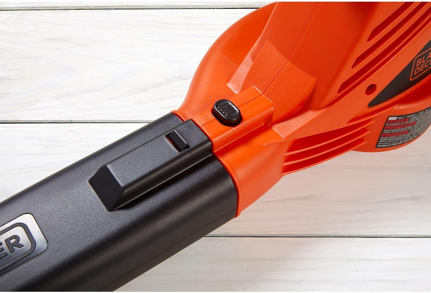 A detailed close-up of the BLACK+DECKER leaf blower's nozzle and the black release button used to detach the tube from the main body.