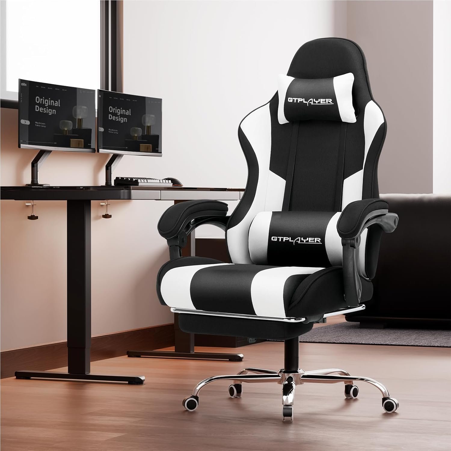 The GTPLAYER black and white gaming chair shown in a modern home office setting next to a desk with dual monitors.
