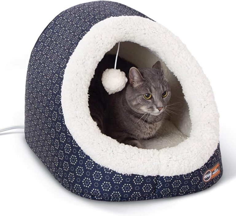 A studio shot of the K&H heated pet cave in a blue and white pattern, with a grey cat resting inside looking out.