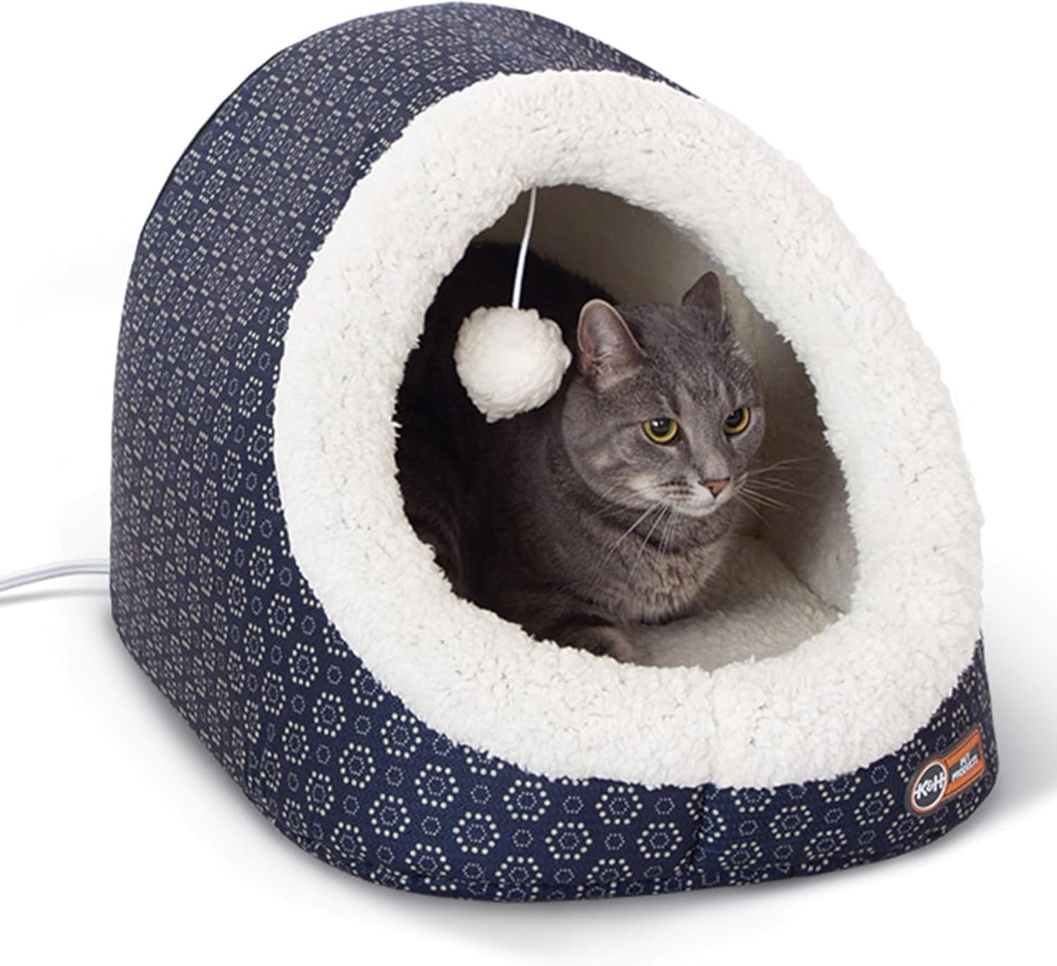 A studio shot of the K&H heated pet cave in a blue and white pattern, with a grey cat resting inside looking out.