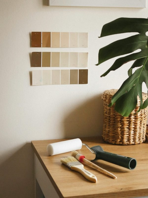 home-improvement-planning-paint-swatches Planning a home improvement project with paint color swatches on the wall and painting tools on a desk.
